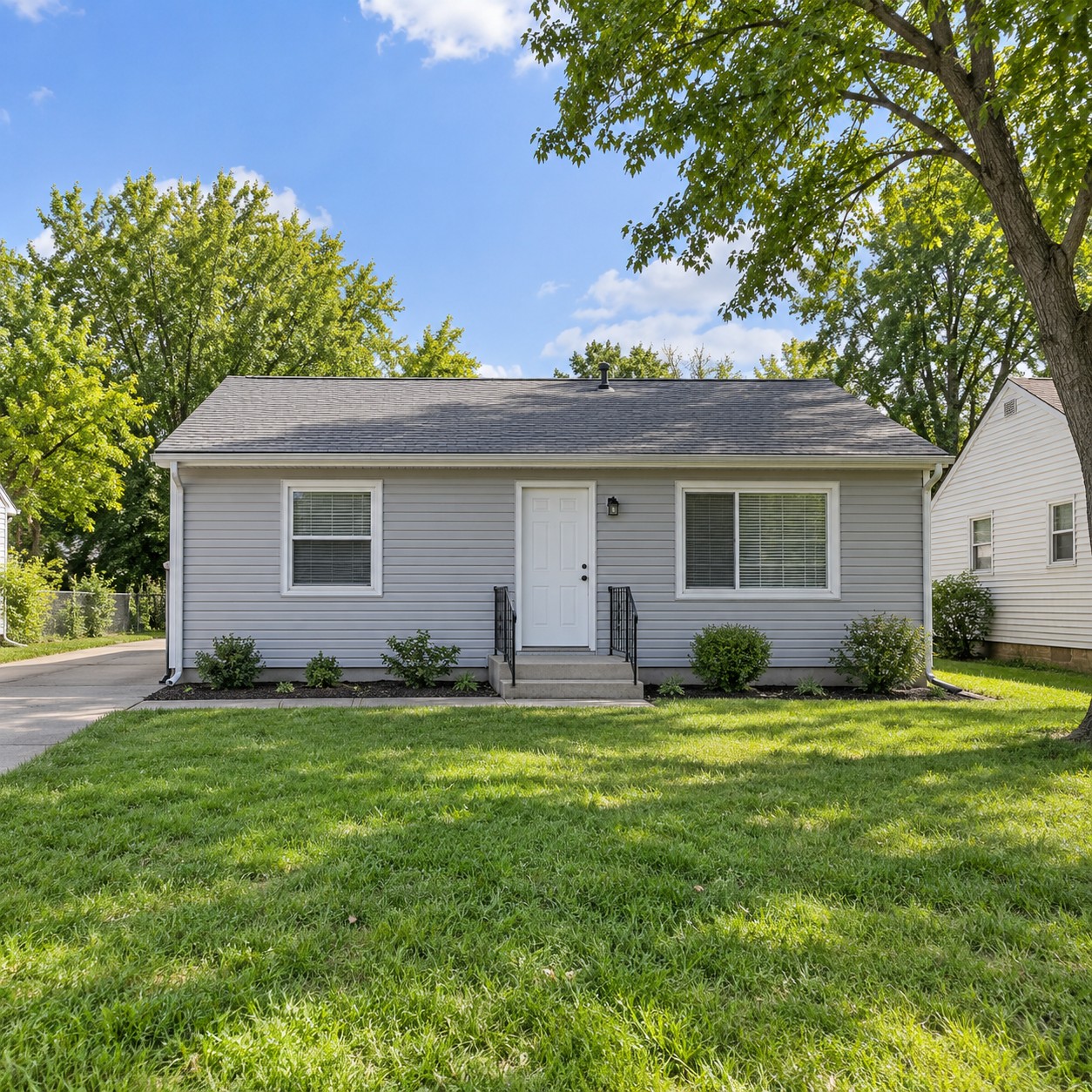 Illustrative modest single-story ranch rental home with gray siding and a small front lawn